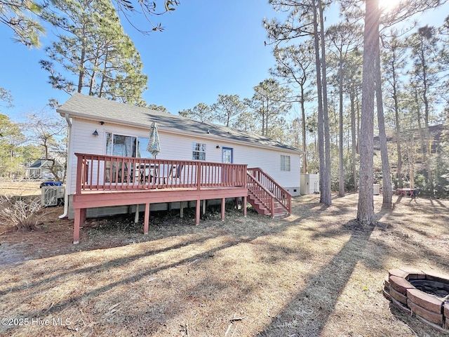 rear view of house with roof with shingles, stairs, a fire pit, and a wooden deck