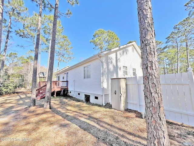 rear view of house with crawl space, fence, and a wooden deck