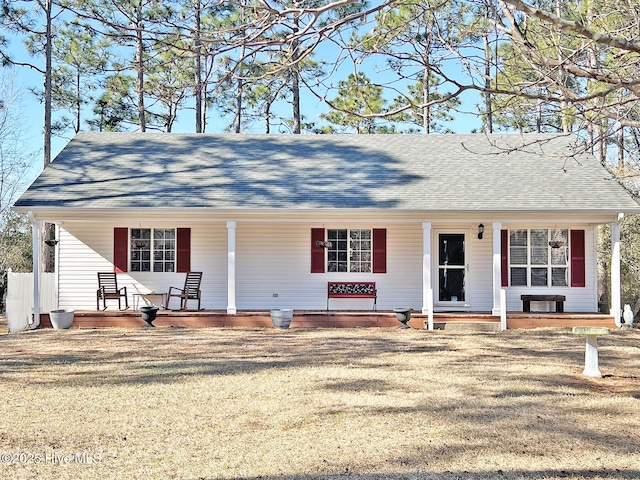 ranch-style home featuring a shingled roof, covered porch, and a front lawn