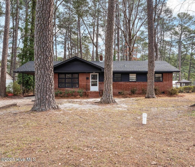 view of front of property featuring roof with shingles, brick siding, and crawl space