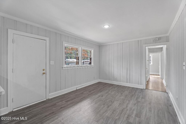 empty room featuring visible vents, crown molding, baseboards, and wood finished floors