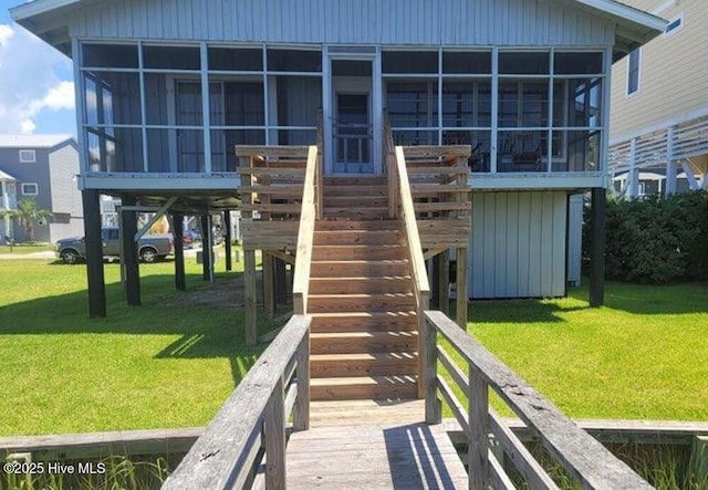 back of property with a sunroom, stairway, and a lawn