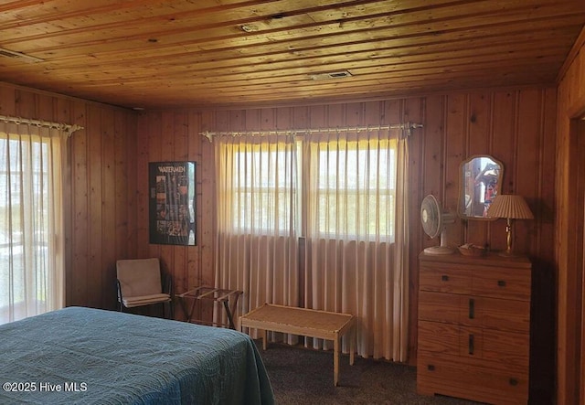 bedroom with carpet, wood ceiling, multiple windows, and wooden walls