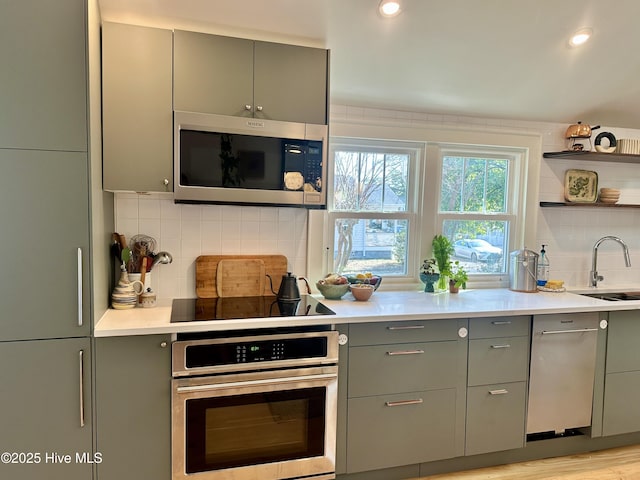 kitchen featuring light countertops, appliances with stainless steel finishes, a sink, and decorative backsplash