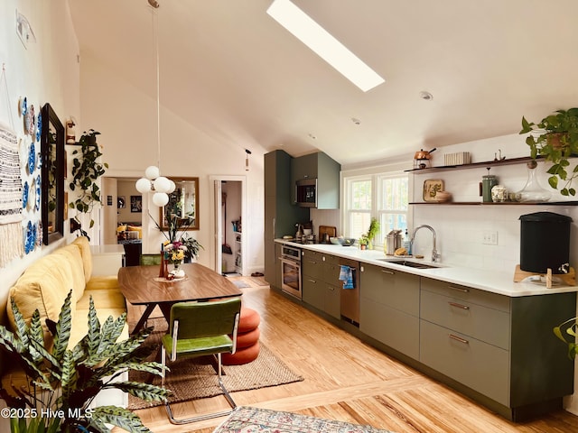 kitchen featuring a skylight, light wood finished floors, stainless steel appliances, light countertops, and a sink