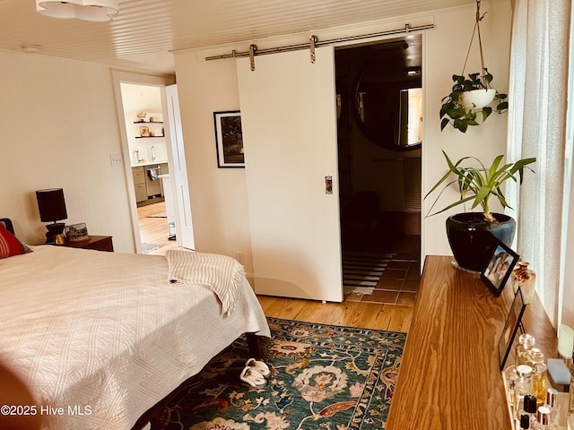 bedroom featuring wood finished floors and a barn door