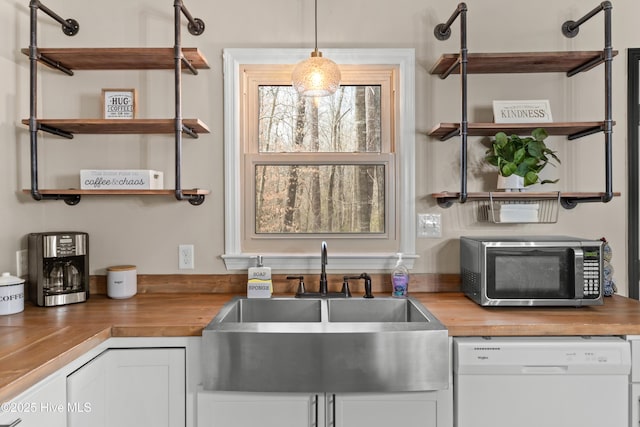 kitchen with wooden counters, open shelves, white dishwasher, a sink, and stainless steel microwave