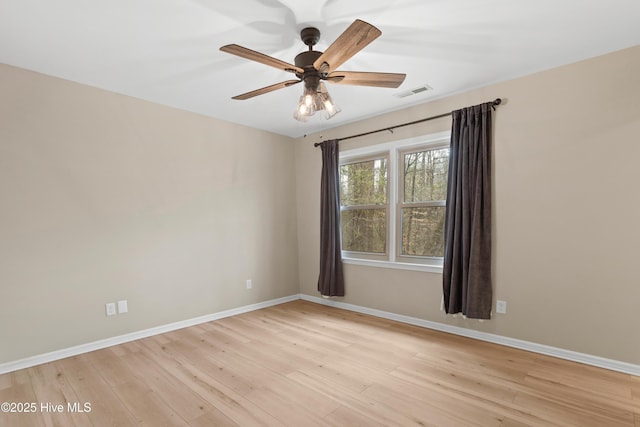 unfurnished room with visible vents, light wood-style flooring, a ceiling fan, and baseboards