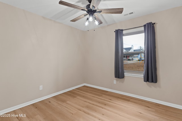 spare room featuring a ceiling fan, wood finished floors, visible vents, and baseboards