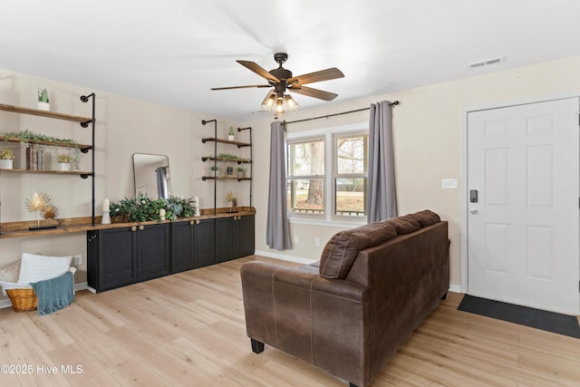 living room with light wood finished floors, visible vents, a ceiling fan, and baseboards