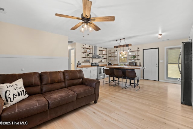 living room featuring light wood finished floors, visible vents, and ceiling fan