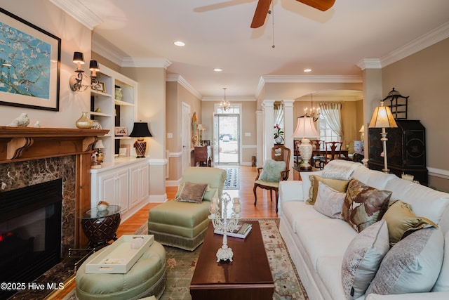 living room with arched walkways, built in shelves, a high end fireplace, ornamental molding, and light wood finished floors