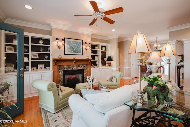 living area featuring light wood finished floors, a ceiling fan, a premium fireplace, crown molding, and recessed lighting