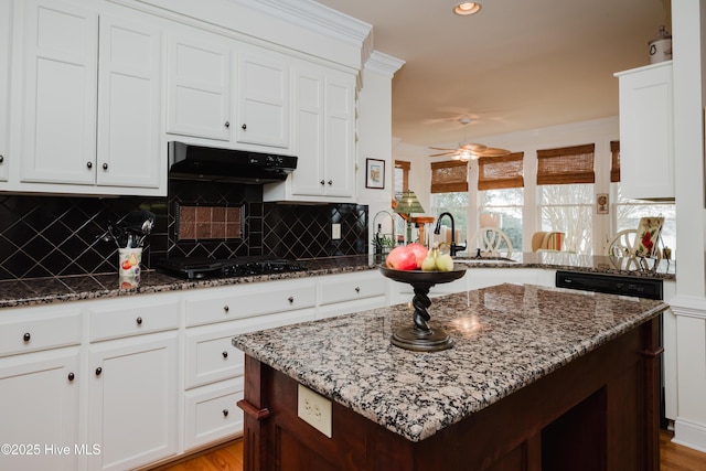 kitchen featuring black gas cooktop, a sink, under cabinet range hood, and dark stone countertops