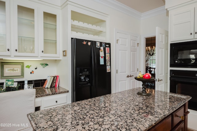 kitchen with white cabinetry, ornamental molding, black appliances, dark stone countertops, and glass insert cabinets