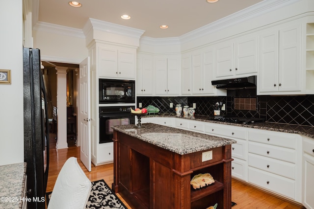 kitchen featuring light wood-type flooring, under cabinet range hood, black appliances, and open shelves