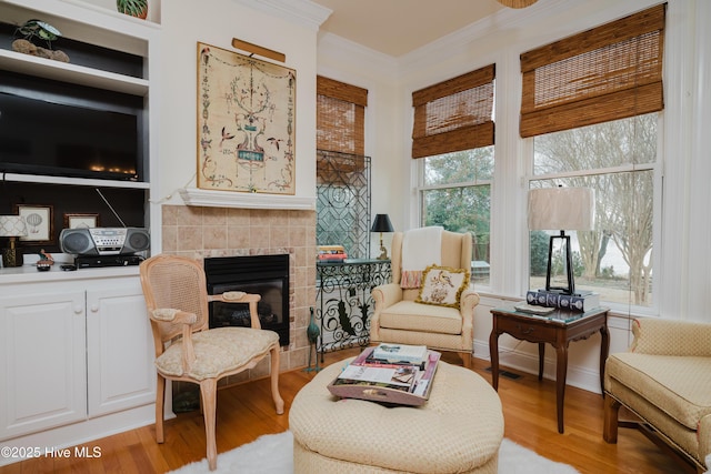 sitting room featuring ornamental molding, a fireplace, and light wood-style flooring