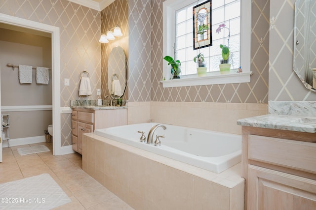 full bathroom featuring two vanities, toilet, tile patterned flooring, baseboards, and a bath