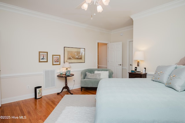 bedroom featuring crown molding, visible vents, a ceiling fan, wood finished floors, and baseboards