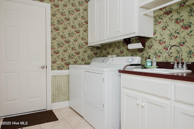 laundry room with wallpapered walls, cabinet space, wainscoting, washing machine and clothes dryer, and a sink