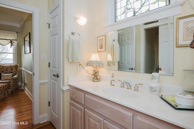 bathroom with ornamental molding, vanity, baseboards, and wood finished floors