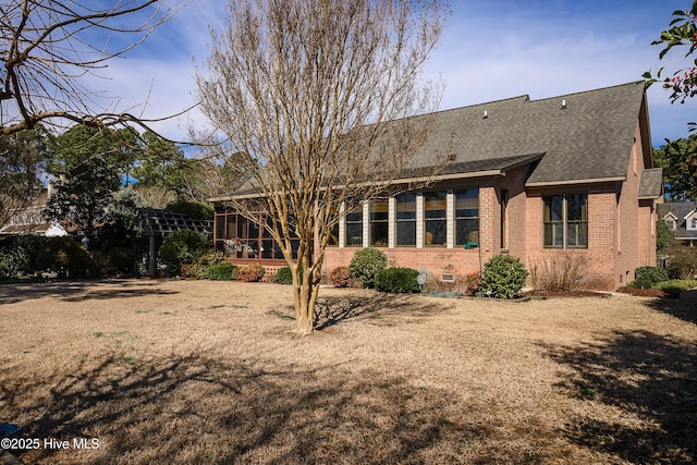 back of house featuring roof with shingles, brick siding, crawl space, and a sunroom