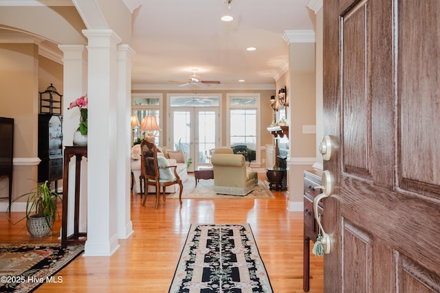 entryway with light wood-style floors, decorative columns, ornamental molding, and french doors