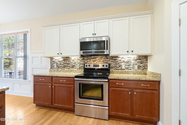 kitchen featuring white cabinets, tasteful backsplash, stainless steel appliances, and light wood-style flooring