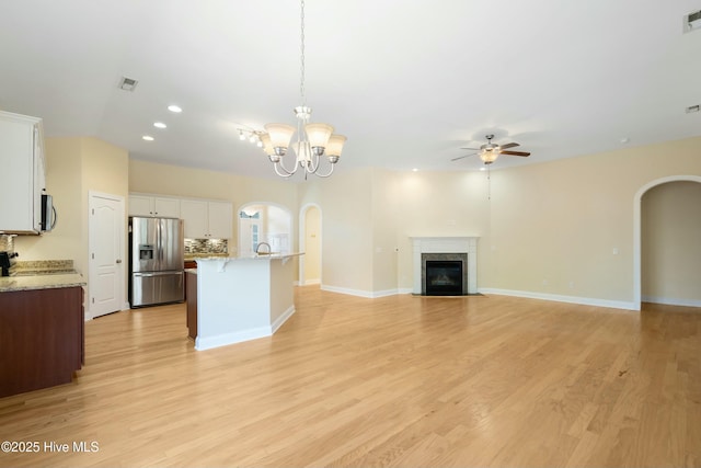 kitchen featuring arched walkways, stainless steel appliances, open floor plan, and white cabinetry