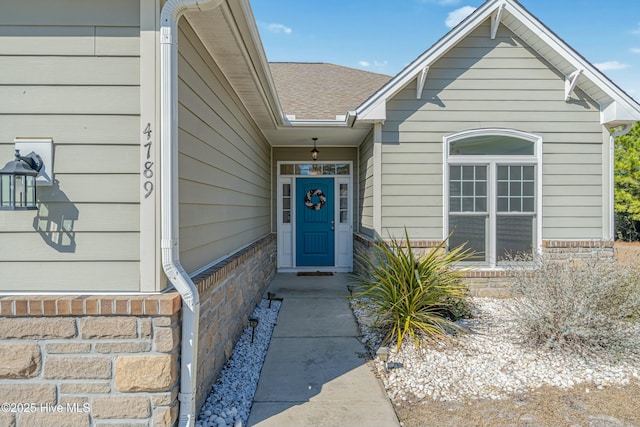 doorway to property featuring roof with shingles