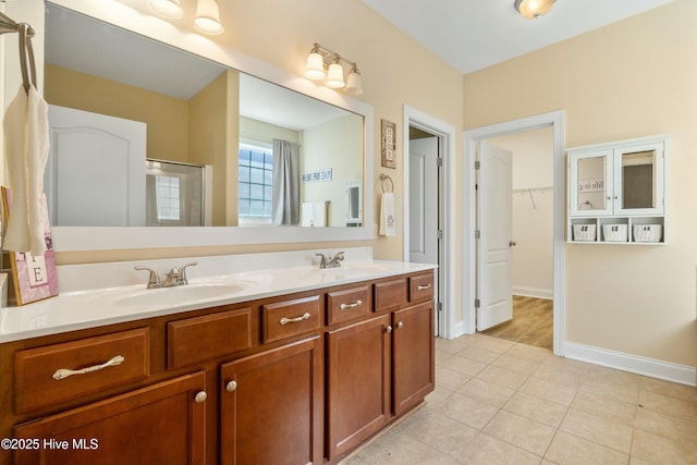 full bath featuring a walk in closet, a sink, a shower stall, and double vanity