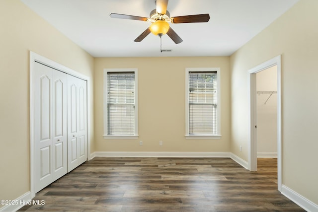 unfurnished bedroom featuring ceiling fan, dark wood-type flooring, visible vents, baseboards, and a closet