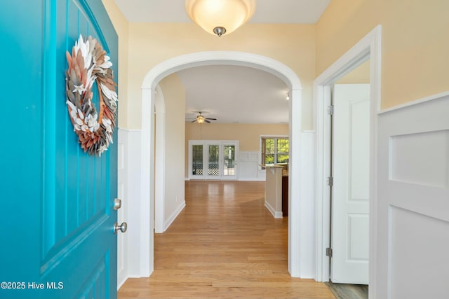 hallway with light wood finished floors and arched walkways