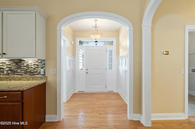 entryway featuring light wood-style floors and arched walkways