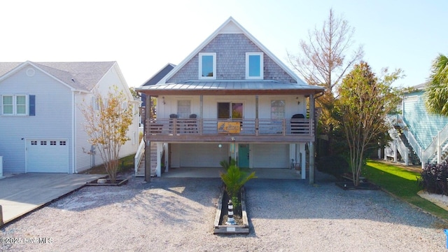 view of front of property with an attached garage, a standing seam roof, driveway, and stairway