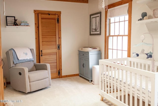 bedroom featuring light carpet, baseboards, and a crib