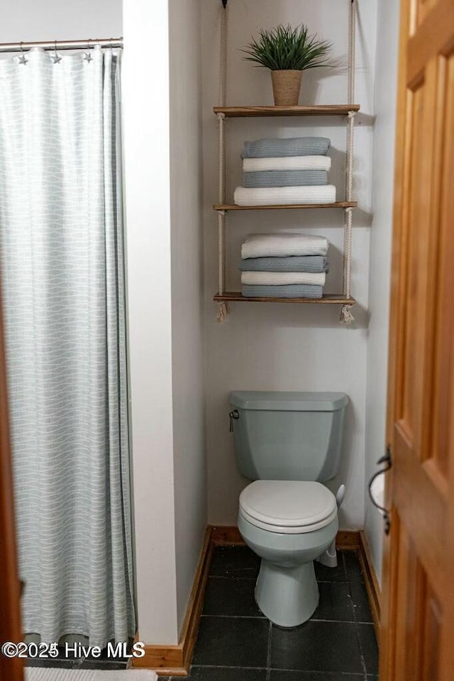 full bath with tile patterned flooring, toilet, and baseboards