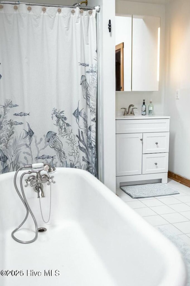 bathroom with a bath, tile patterned flooring, vanity, and baseboards