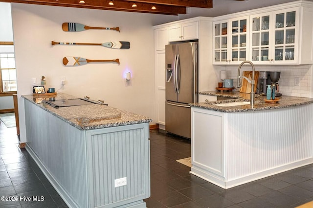 kitchen with glass insert cabinets, white cabinets, a sink, and stainless steel fridge with ice dispenser