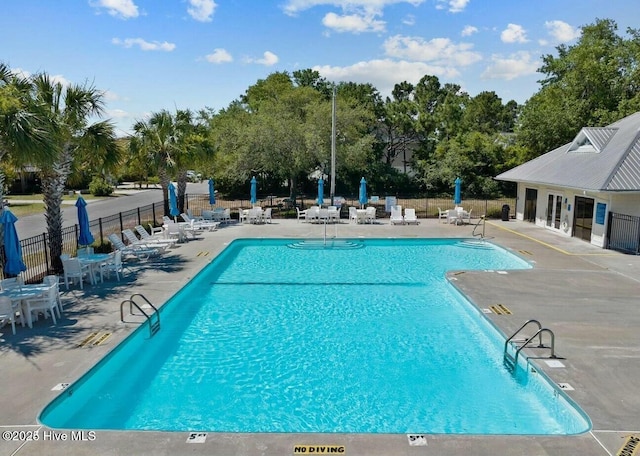 community pool with a patio area and fence