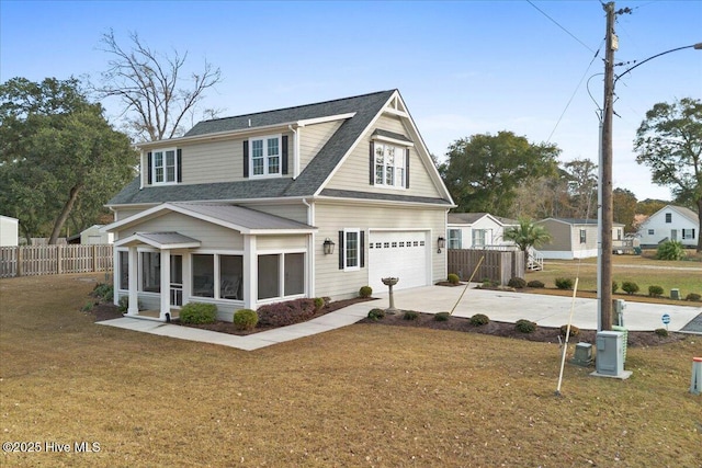 view of front of house with an attached garage, a front yard, a sunroom, fence, and driveway