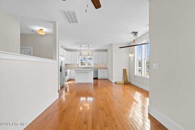 unfurnished living room featuring baseboards, ceiling fan, visible vents, and light wood-style floors