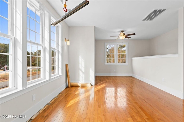 unfurnished room with light wood-type flooring, visible vents, plenty of natural light, and baseboards