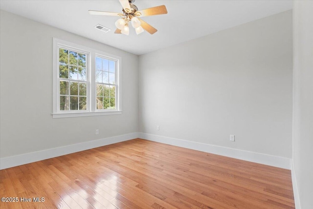 spare room featuring a ceiling fan, light wood-type flooring, visible vents, and baseboards