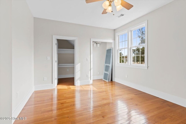 unfurnished bedroom featuring light wood-style flooring, a ceiling fan, visible vents, and baseboards