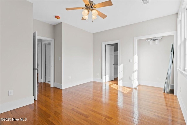 unfurnished bedroom with visible vents, light wood-style flooring, a spacious closet, ceiling fan, and baseboards