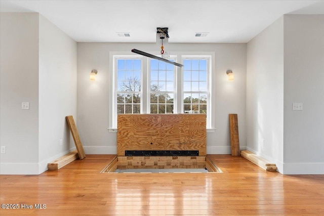 unfurnished dining area with light wood finished floors, visible vents, and baseboards