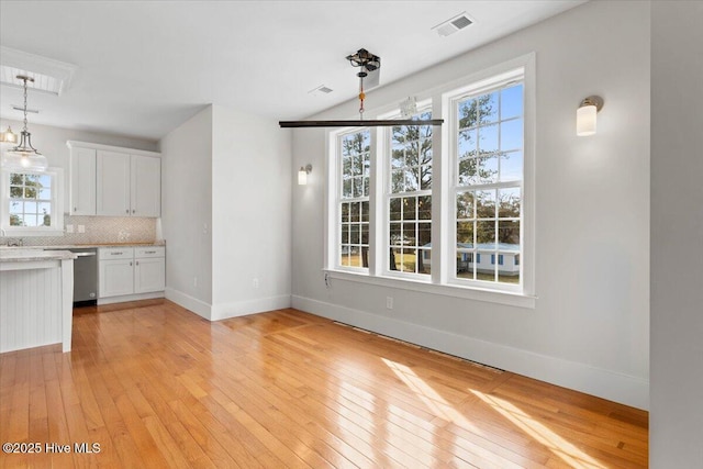 unfurnished dining area featuring visible vents, light wood-style flooring, and baseboards