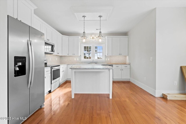 kitchen featuring appliances with stainless steel finishes, a center island, decorative light fixtures, and white cabinets