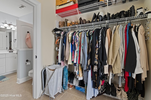 walk in closet with light tile patterned floors, visible vents, and a sink